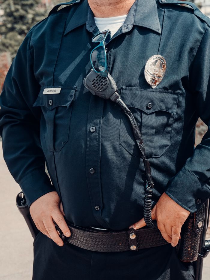 services-01 Close-up view of a police officer wearing a dark uniform with badge and radio microphone.